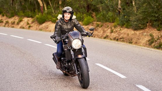 A rider on top of a futuristic looking motorcycle, enjoying a ride on an empty road.