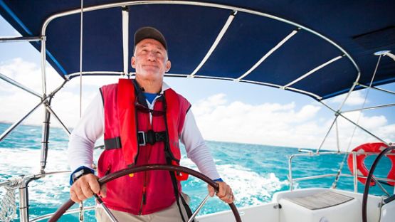 A tight shot of a person at the wheel of a contemporary cabin cruiser.