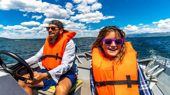 Father and daughter wearing life jackets on a small boat enjoying a day out on the water.