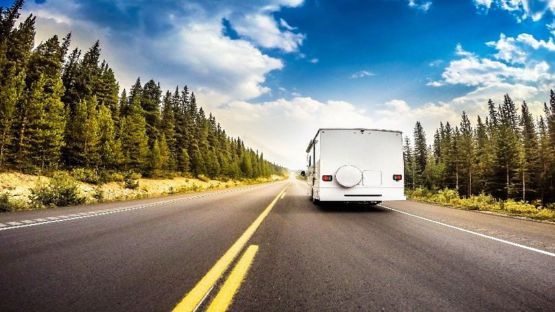 RV Motorhome on a highway surrounded by trees